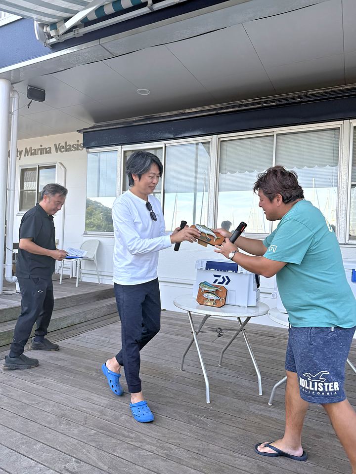 デッキで後藤幹事長から Rising Kai のメンバーへ楯が手渡される場面