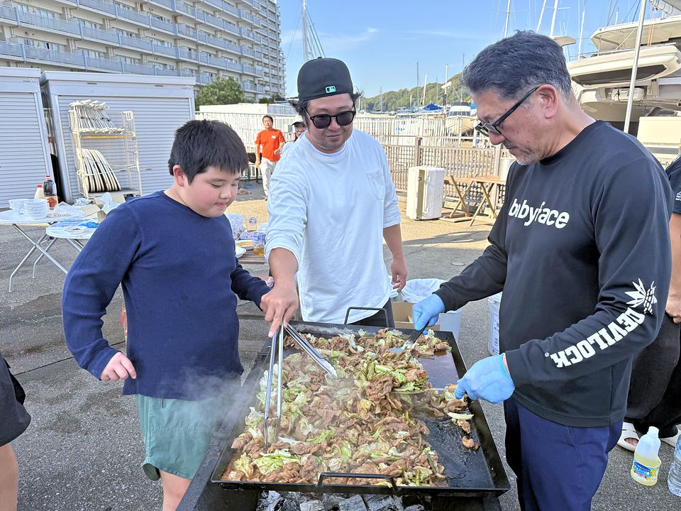 鉄板で肉と野菜を焼く参加者と子ども