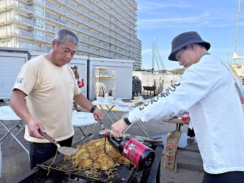 大きな鉄板で焼きそばを焼く参加者