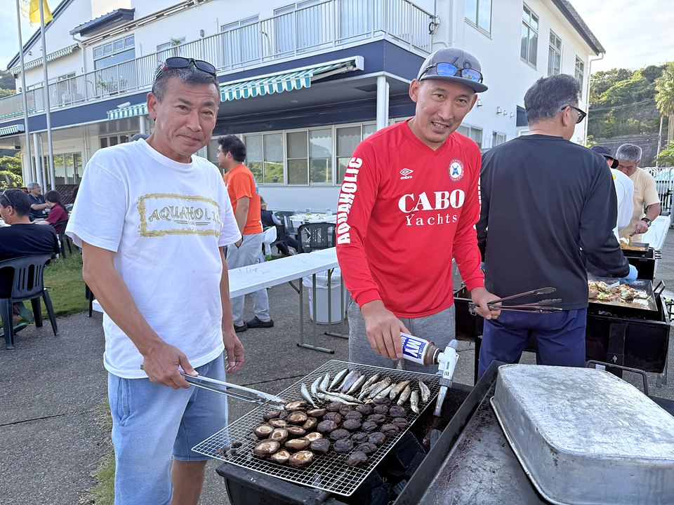 炭火の網でしいたけと魚を焼く参加者