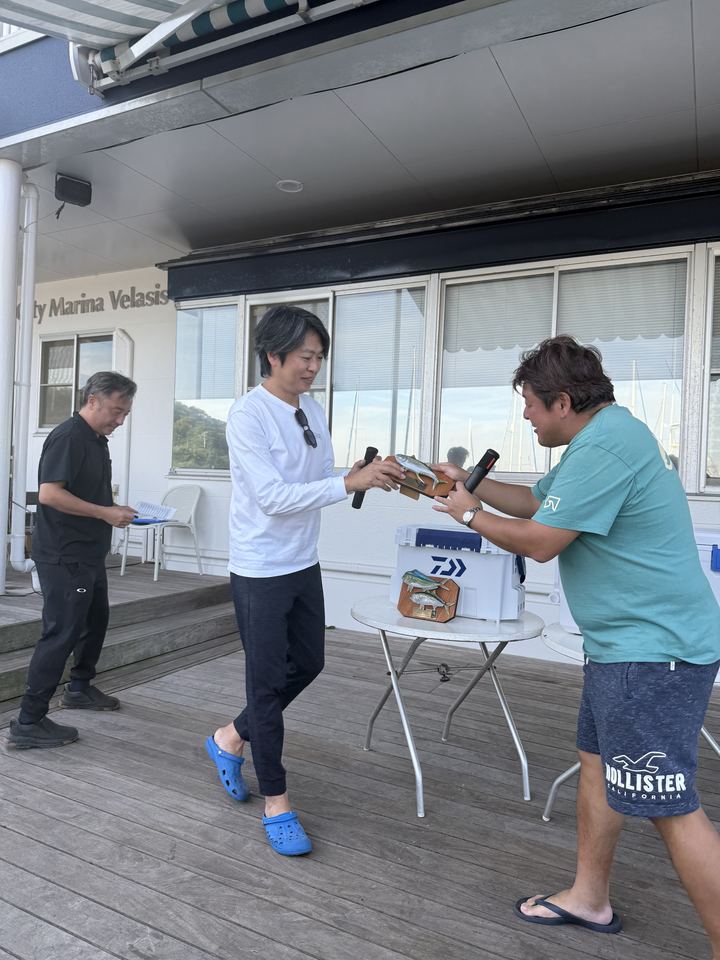デッキで後藤幹事長から Rising KAI のメンバーへ楯が手渡される場面