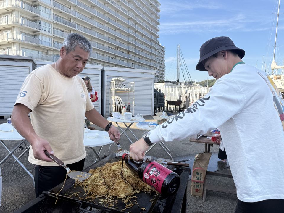 大きな鉄板で焼きそばを焼く参加者