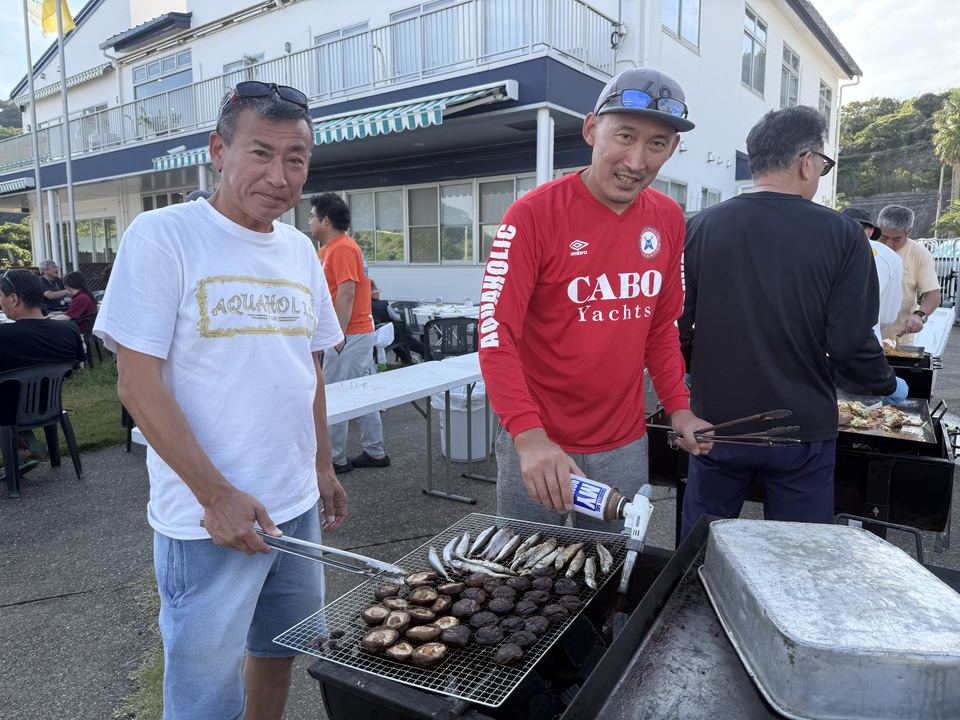 炭火の網でしいたけと魚を焼く参加者